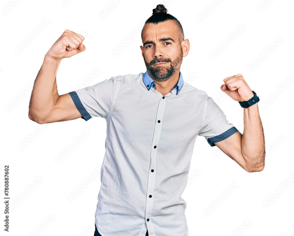 Hispanic man with ponytail wearing casual white shirt showing arms muscles smiling proud. fitness concept. Hispanic man with ponytail wearing casual white shirt showing arms muscles smiling proud. fitness concept.
