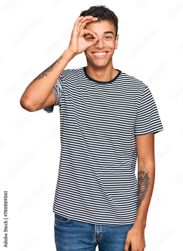 Young handsome african american man wearing casual clothes doing ok gesture with hand smiling, eye looking through fingers with happy face. Young handsome african american man wearing casual clothes doing ok gesture with hand smiling, eye looking through fingers with happy face.