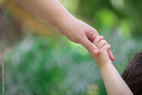 Family holding children hands walking through a park together  © natrocfort