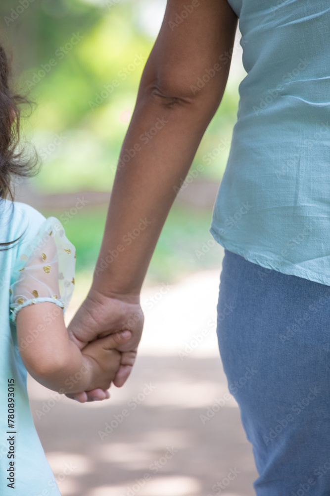 Family holding children hands walking through a park together 