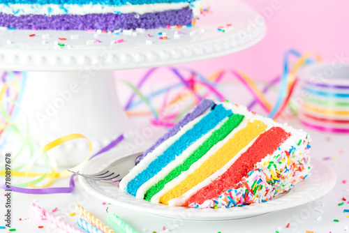 A slice of rainbow birthday cake with colourful sprinkles  ready for eating.