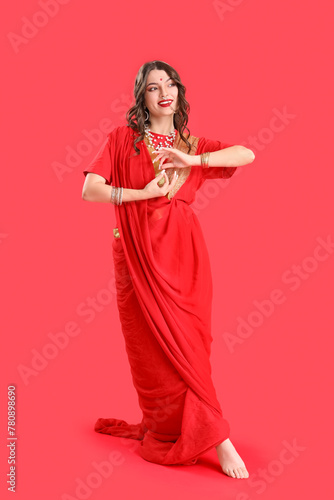 Beautiful young Indian woman in sari on red background