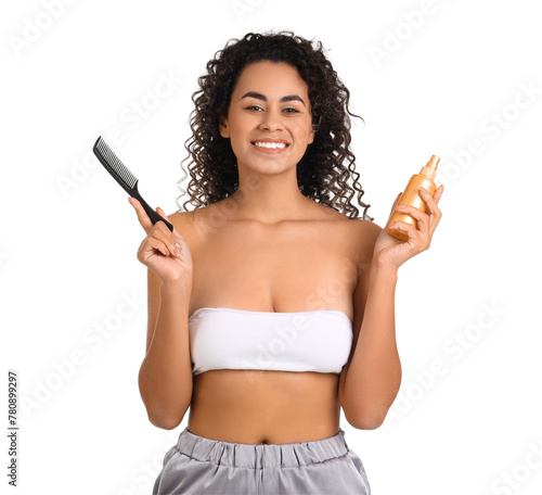 Beautiful African-American woman with hair spray and comb on white background