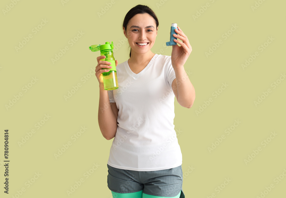 Sporty young woman with inhaler and water bottle on green background Sporty young woman with inhaler and water bottle on green background