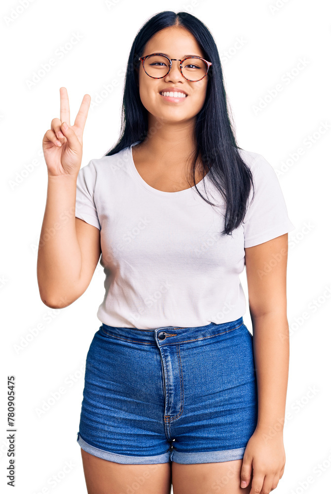 Young beautiful asian girl wearing casual clothes and glasses smiling looking to the camera showing fingers doing victory sign. number two. Young beautiful asian girl wearing casual clothes and glasses smiling looking to the camera showing fingers doing victory sign. number two.