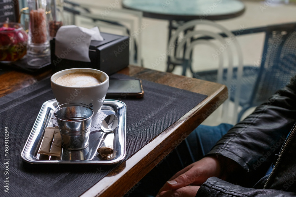 A cup of hot latte on a wooden table in the warm afternoon sun.