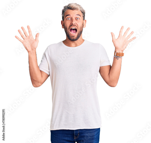 Young handsome blond man wearing casual t-shirt pointing fingers to camera with happy and funny face. good energy and vibes.