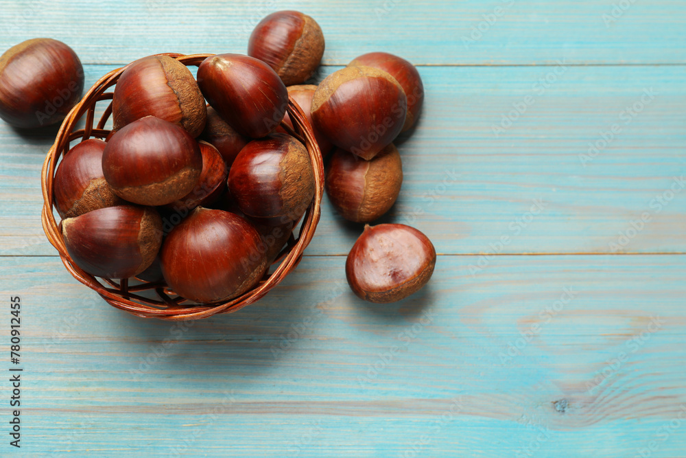 Wicker bowl with roasted edible sweet chestnuts on light blue wooden table, flat lay. Space for text Wicker bowl with roasted edible sweet chestnuts on light blue wooden table, flat lay. Space for text