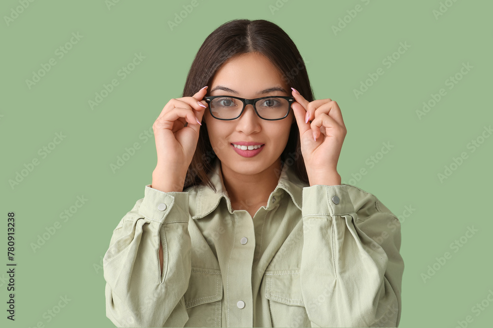 Beautiful young happy Asian woman with new eyeglasses on green background Beautiful young happy Asian woman with new eyeglasses on green background