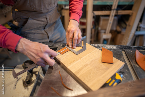 Male hands cutting leather skin. Master measures right amount, uses caliper and construction knife, makes leather covers for the bed legs to prevent them from scratching floor. photo