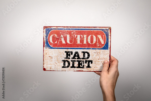 Fad Diet. Metal warning sign in a woman's hand on a white background © STOATPHOTO