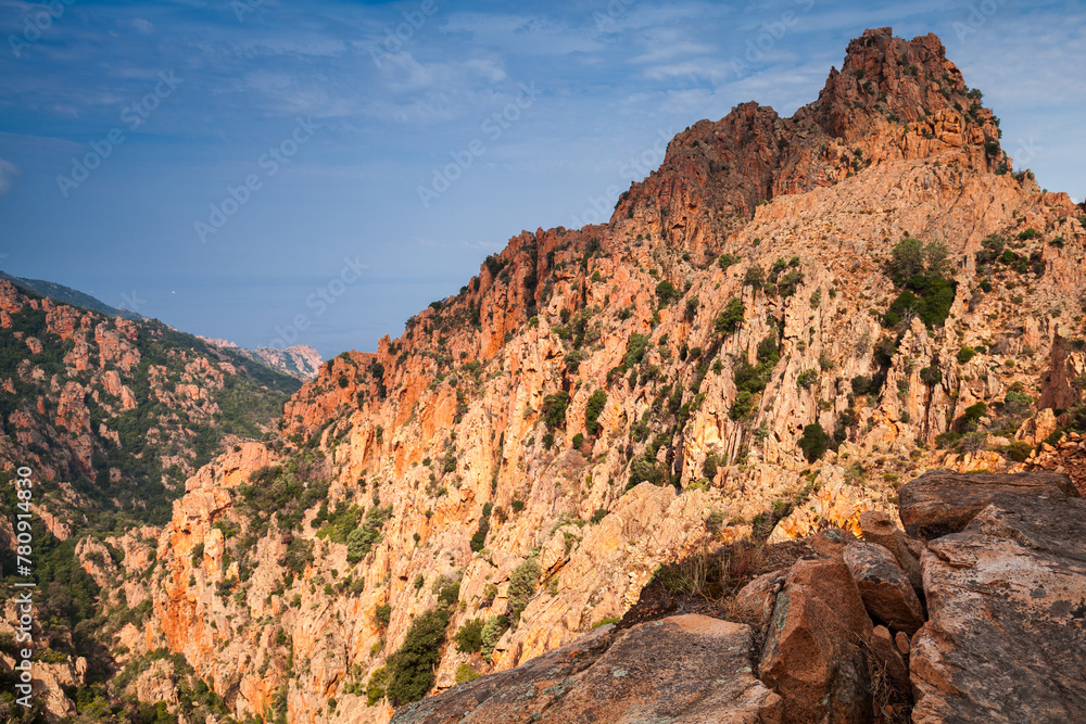 Fototapeta premium Red rocks of Calanques de Piana are under blue cloudy sky, Corscia