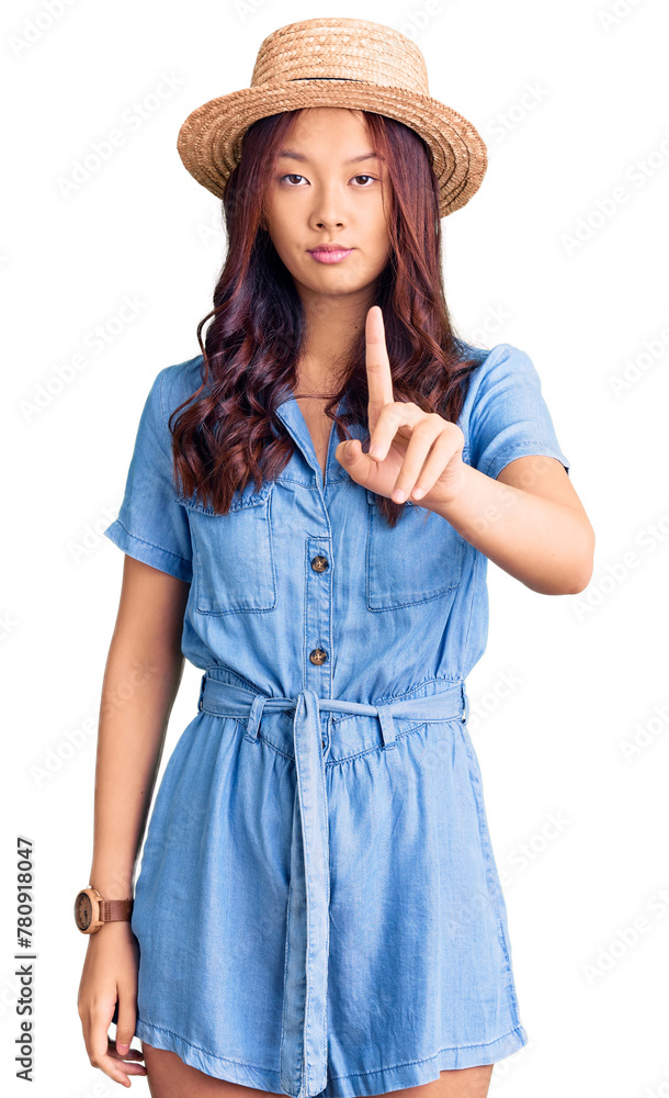 Young beautiful chinese girl wearing summer hat pointing with finger up and angry expression, showing no gesture Young beautiful chinese girl wearing summer hat pointing with finger up and angry expression, showing no gesture