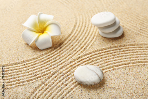 Spa stones and plumeria on light sand with lines. Zen concept