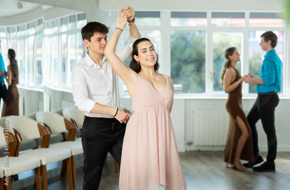 While doing rehearsal of reporting concert, guy and girl participants of dance workshop perform quickstep. Two couples practice their skills in performing quickstep during attending dancing school.