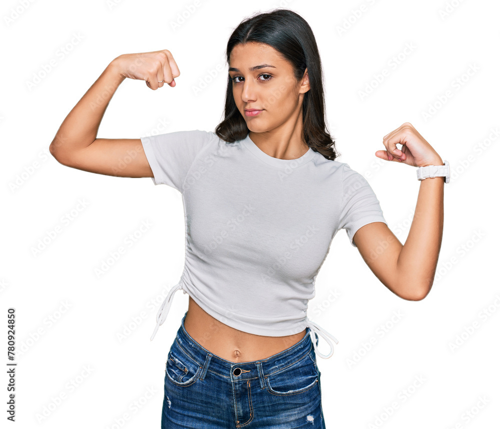 Young hispanic girl wearing casual white t shirt showing arms muscles smiling proud. fitness concept.