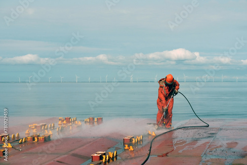 Safety Equipped Crew Seaman Working On Deck With Jet Water Blast Machine Gun To Remove Prevent Corrosion