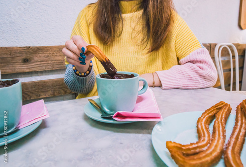 Teenage girl is eating a chocolate covered churro with a blue nail polish.