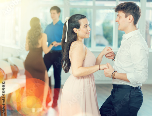 With music, guy with girl in couple spins to rhythm of paso doble during lesson on parquet. Classes in mini-groups, participants of class enjoy movement, learn to control body in dance
