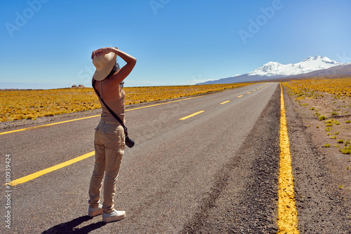 rear view young woman traveler adventurer standing on the road contemplating beautiful altiplano in Los Flamencos National Reserve Antofagasta Region San Pedro de Atacama photo