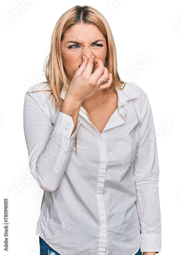 Young caucasian woman wearing casual clothes smelling something stinky and disgusting  intolerable smell  holding breath with fingers on nose. bad smell