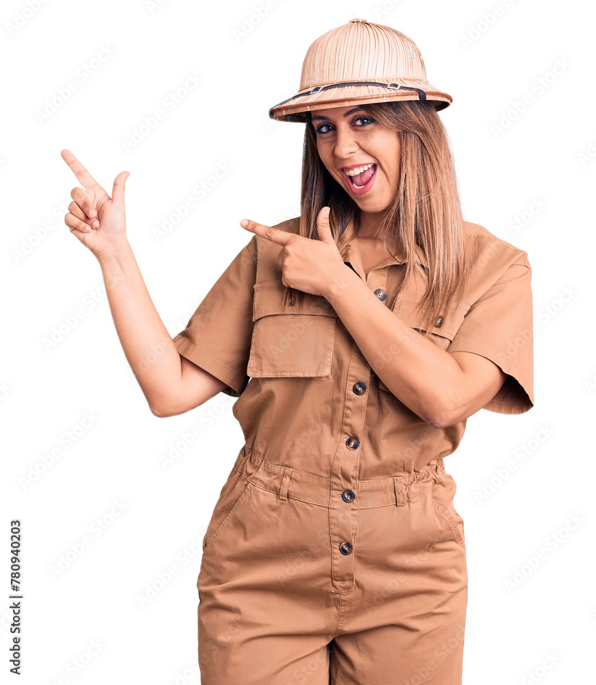 Young beautiful woman wearing explorer hat smiling and looking at the camera pointing with two hands and fingers to the side. Young beautiful woman wearing explorer hat smiling and looking at the camera pointing with two hands and fingers to the side.