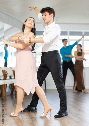Couple in festive clothes learn to dance latin american dance bachata in studio
