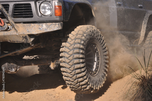 Part of an off-road vehicle overcoming an obstacle on dry dirt, in a mountain