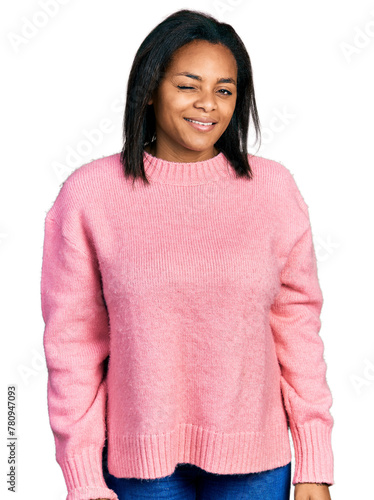 Beautiful hispanic woman wearing casual winter sweater winking looking at the camera with sexy expression, cheerful and happy face.