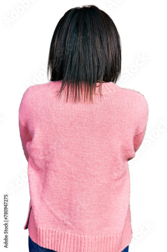 Beautiful hispanic woman wearing casual winter sweater standing backwards looking away with crossed arms