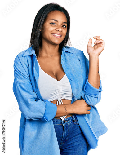 Beautiful hispanic woman wearing casual denim jacket with a big smile on face, pointing with hand and finger to the side looking at the camera.