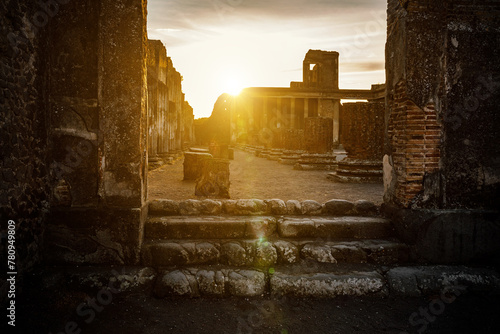 An ancient, partially ruined temple stands bathed in the golden hue of a setting sun. photo