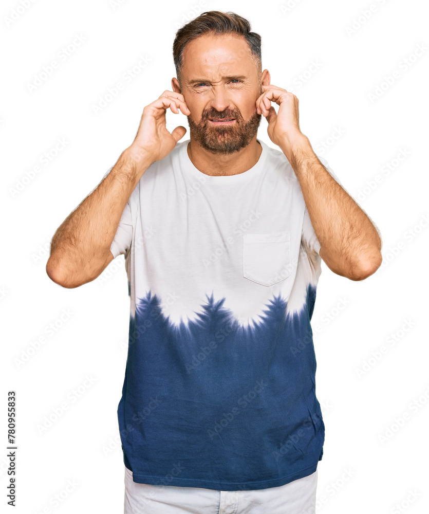 Handsome middle age man wearing casual tie dye tshirt covering ears with fingers with annoyed expression for the noise of loud music. deaf concept. Handsome middle age man wearing casual tie dye tshirt covering ears with fingers with annoyed expression for the noise of loud music. deaf concept.