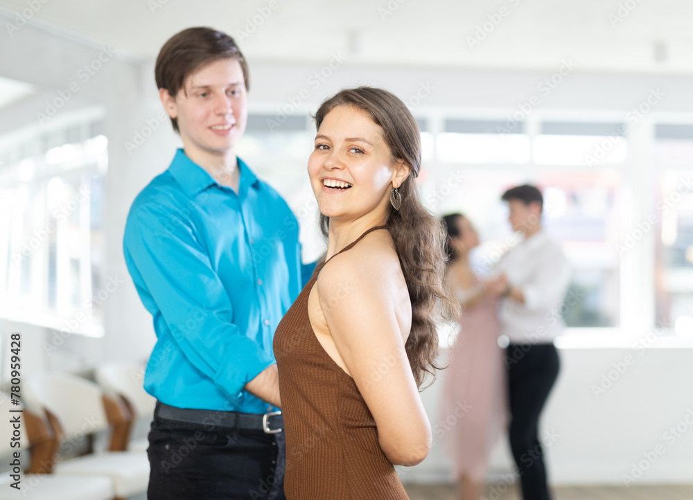 Fototapeta premium Smiling attractive young female dancer practicing passionate samba with positive elegant guy in dance class. Amateur dancing concept..