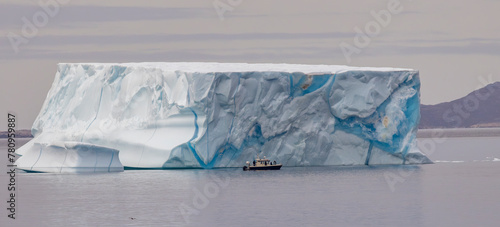 huge Iceberg in Greenland harbor with boat for size comparison