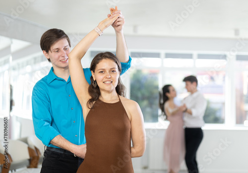 Positive elegant couple, young girl and guy in formal wear dancing sensual Latin dance bachata in sunlit choreography studio. Active lifestyle of youth..