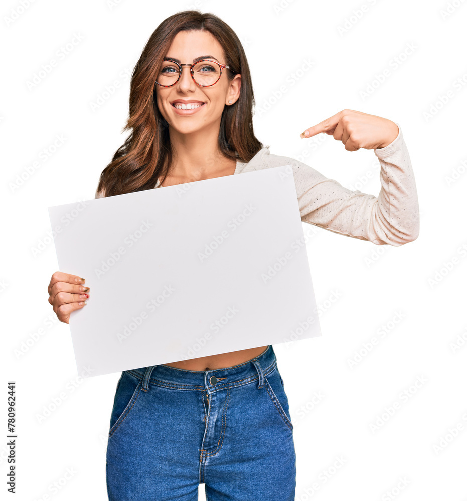 Young brunette woman holding blank empty banner pointing finger to one self smiling happy and proud Young brunette woman holding blank empty banner pointing finger to one self smiling happy and proud