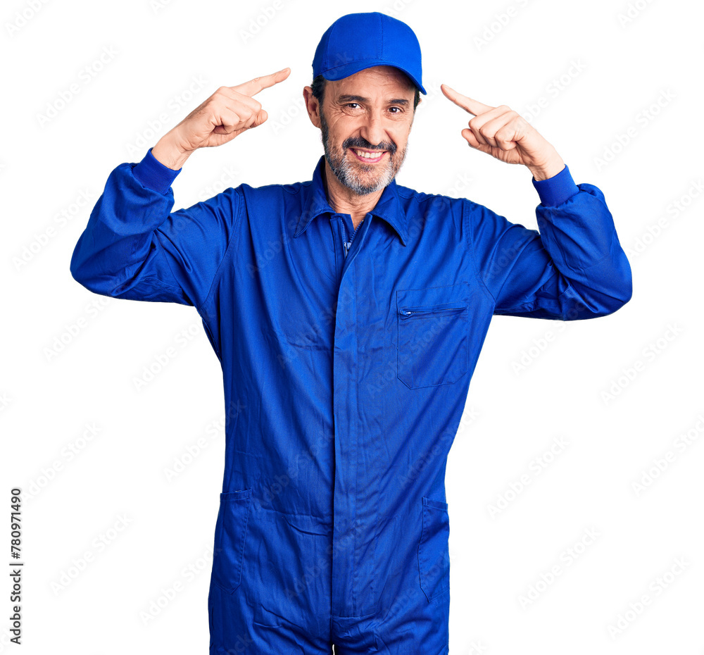 Middle age handsome man wearing mechanic uniform smiling pointing to head with both hands finger, great idea or thought, good memory