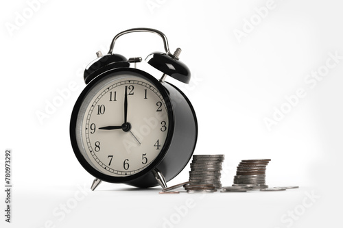 Black alarm clock with stack of coin on white background.