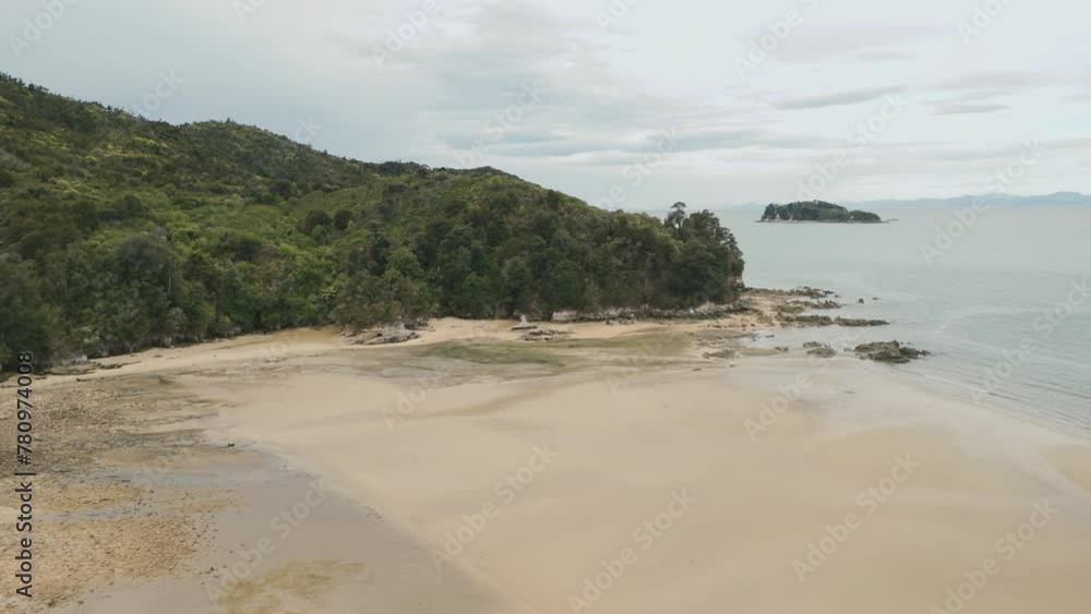 Green hills and wide yellow sand beach during outflow in New Zealand Green hills and wide yellow sand beach during outflow in New Zealand