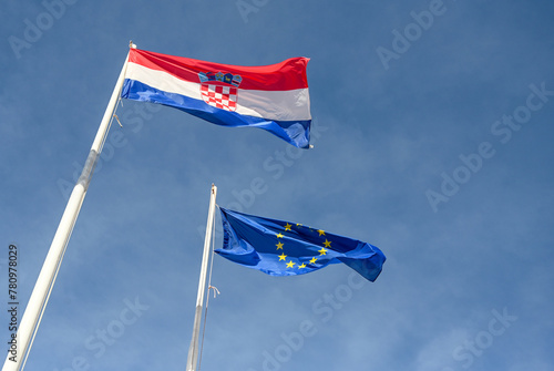 Croatian and EU flags waving in the wind. Flags of Croatia and European Union flying on a pole.  