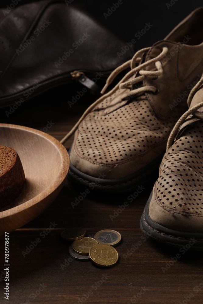 Poverty. Old shoes, bag, piece of bread and coins on wooden table - obrazy, fototapety, plakaty 
