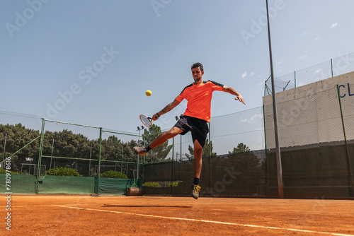 Man in sportswear playing tennis on a dirt tennis court © PEDROMERINO