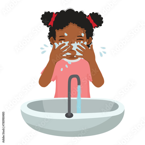 Cute little African girl washing face in the sink
