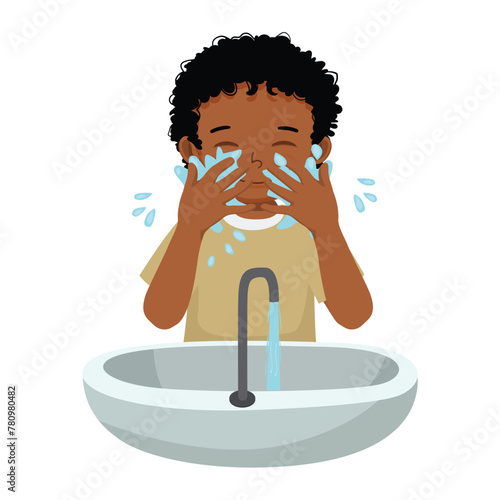 Cute little African boy washing face in the sink