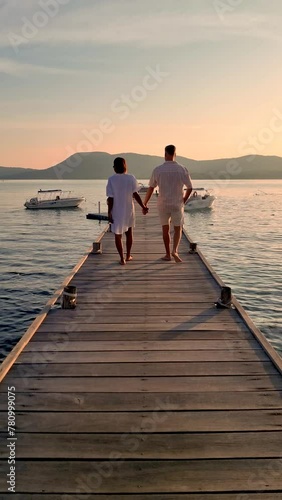 A man and a woman standing on a dock by the ocean, holding hands admiring the horizon. Their gestures express happiness and contentment as they enjoy the leisure of being in nature, Samaesarn Thailand photo