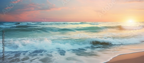 Ocean waves crash as the sun sets on the horizon, painting the sky in warm hues of orange and pink