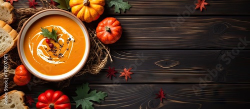 Bowl of pumpkin soup topped with heavy cream, served on a dark rustic wooden table with red bell pepper toasts. Autumn and Thanksgiving background.
