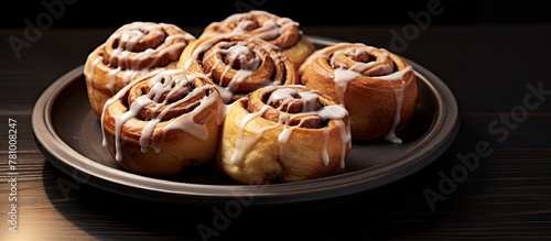 Close-up shot of a delicious plate of cinnamon rolls coated in sweet icing on a table