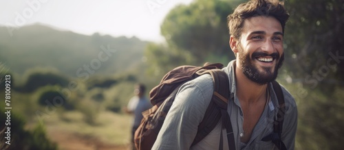 A content man with a backpack is smiling as he walks along a countryside hiking trail in an open field